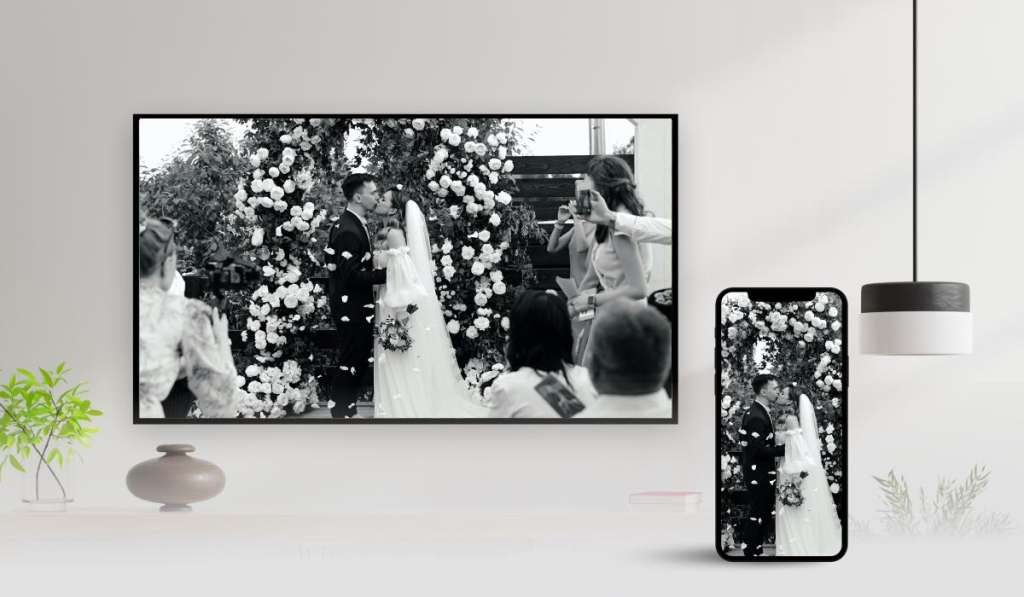 Screen  mirroring a black and white image of wedding couple kissing next to a wall of flowers